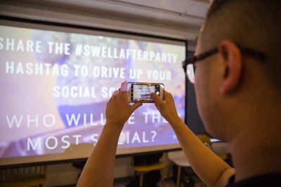 A guest snaps a picture of the social wall at an event.
