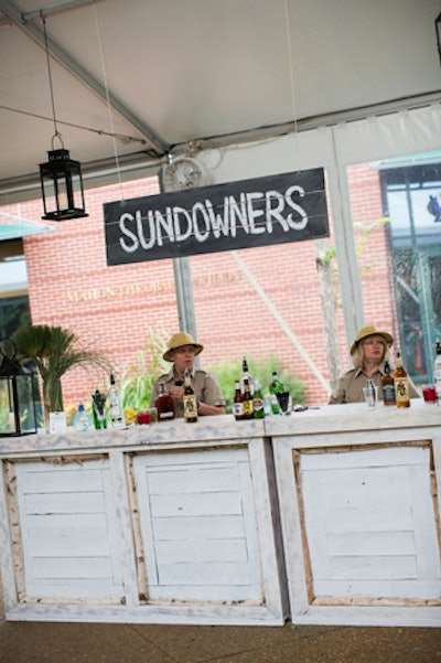 The cocktail reception featured a custom, 32-foot bar adorned with vintage-inspired 'sundowner' drink signs. Elsewhere in the tent, burlap-wrapped food carts held appetizers. The bar was designed by Northern Decor and Logistics.