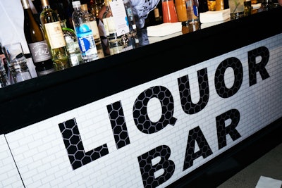 Bold, capitalized letters on a contrasting white tiled backdrop let attendees know where they could grab cocktails.