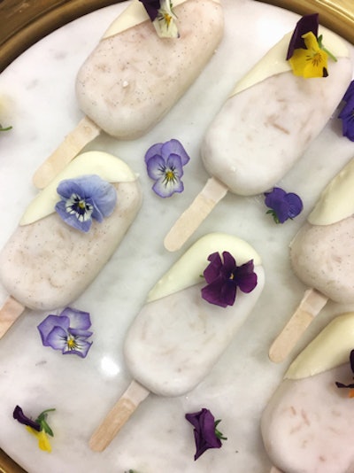 Coconut popsicles dipped in white chocolate and garnished with edible flowers, by Starr Catering Group in South Florida