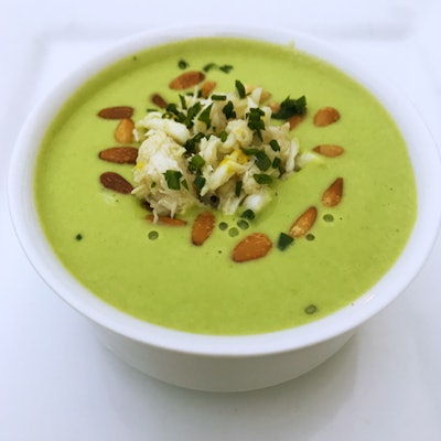 Chilled sweet-pea soup made with fresh spring peas, cream, and vegetable stock and finished with Louisiana crab, goat cheese crème fraîche, and toasted pine nuts, by Joel Catering and Special Events in New Orleans