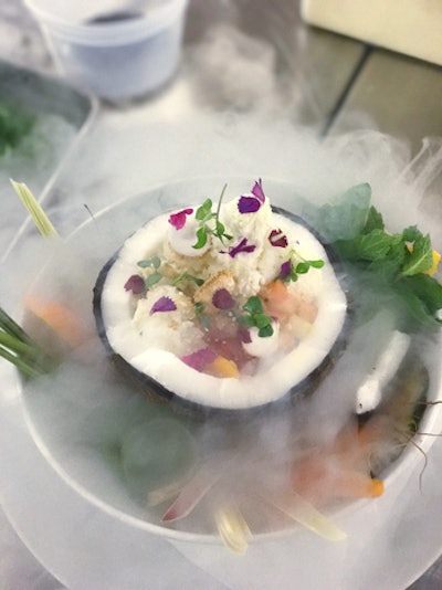 A tropical sundae layered with ginger tapioca, lime granita, honey-kissed coconut marshmallow, passion-fruit glaze, and cardamom ice cream over melon ball salsa, served in a frozen coconut shell and surrounded by smoking mist, by Starr Catering Group in South Florida