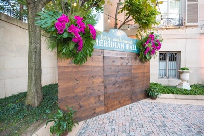The step-and-repeat in the Meridian House courtyard incorporated tropical florals and the whimsical design and lettering used in the ball invitations.