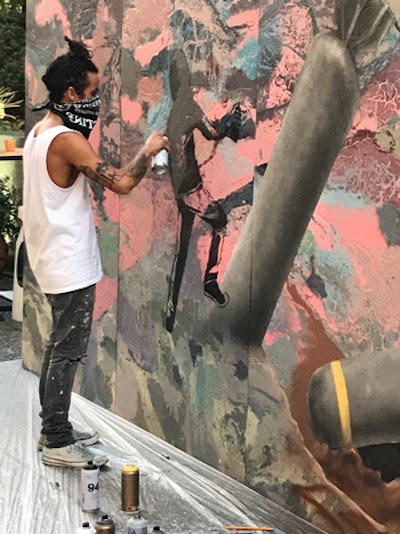 Throughout the evening, local street artist Bandit use spray paint on a 10- by 30-foot canvas, creating a mural promoting world peace.