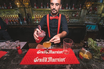 A mixologist crafted a welcome cocktail, the Grand Marnier Sidecar, at a branded bar.