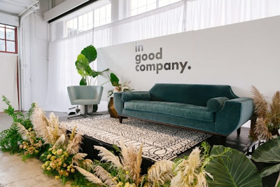 The main stage inside Gallery 308 at Fort Mason—a large cultural center overlooking the San Francisco Bay—featured a plush green sofa, a patterned rug, and greenery by Natalie Bowen Designs. Bright Event Rentals provided furniture.
