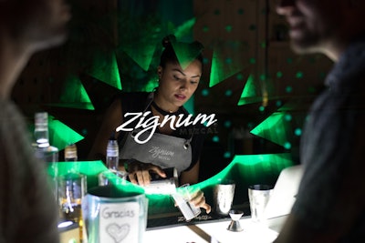 A bar for Zignum Mezcal cocktails featured green and white logo projections.