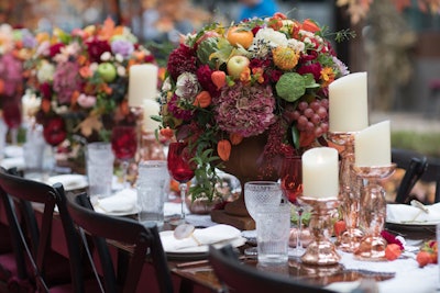 The 32-foot-long dining table in the center of the eye-catching OceanSpray bog was anchored by oversize autumnal floral arrangements of lush blossoms, greens, and fruits. Handmade crocheted table runners were paired with rose-gold glass candleholders.