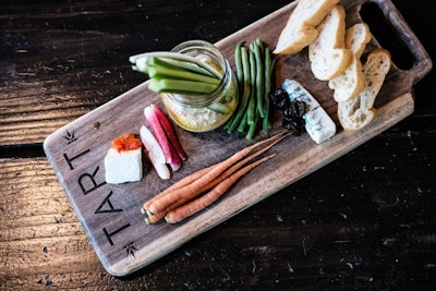 For a healthy, visually appealing cheese board, Tart Restaurant at Farmer’s Daughter Hotel in Los Angeles serves a veggie option featuring green beans, baby carrots, celery sticks, sliced radishes, hummus, and prunes.