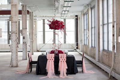 For a Valentine’s Day-theme photo shoot, Rocket Science Weddings & Events designed a modern, industrial-meets-romantic wedding ceremony. Taking place at Machine Shop in Minneapolis, the tabletop had a mix of textures, including black leather linen from Nuage Designs and pink chiffon-draped chair backs from Avant Decor. An arrangement of red flowers made a dramatic statement on a tall stand from Event Lab.