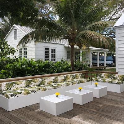 The Penelope Bench with Monstera Print from Ronen Rental is a nod to the tropical South Florida scenery with a clean, white painted wood base and palm leaf-adorned cushions. It's available for indoor and outdoor events, and costs $215.