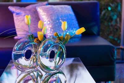 Throughout the event, mirrored furniture and chrome finishings were used to create illusions with the reflections, further tying into the theme. The Garden Gate provided flowers in rounded, clear vases.