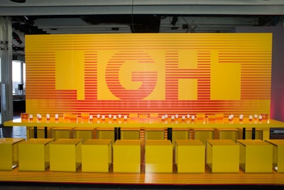 Interior Design magazine continued to use bold graphics and inspiring messages for its tablescape. This year, with the theme 'the light within,' the design featured bright yellow cubes and light bulbs as tabletop decor.