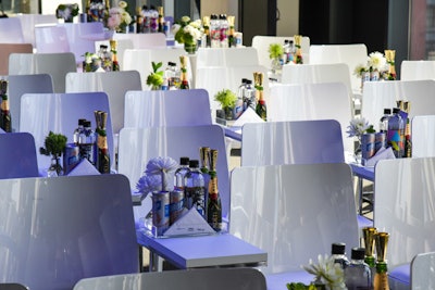 Each table centerpiece consisted of a transparent tray that contained water bottles, canned rosé wine, mini champagne bottles, and a flower arrangement.