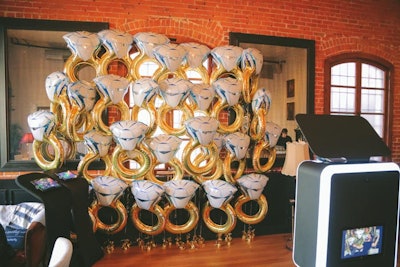 Guests could pose at a photo booth in front of a wall of engagement ring-style balloons.