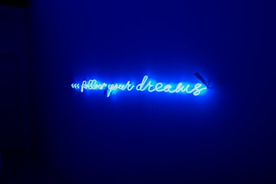 After leaving the laundromat, guests pass through a blue-lit room with a neon sign that reads 'Follow your dreams.'