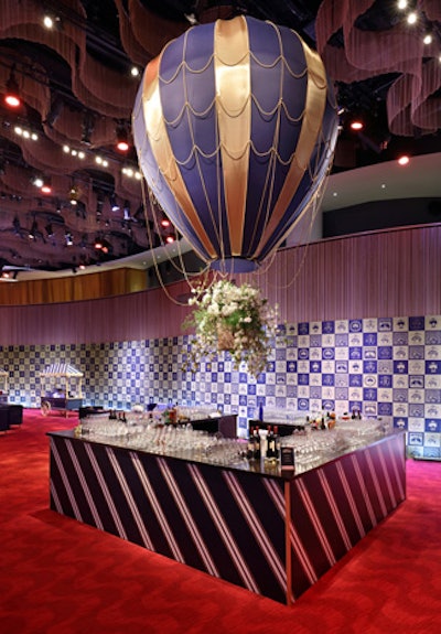 The Atrium served as the central party space and included a number of show-stopping elements, the most prominent of which was a larger-than-life vintage hot air balloon with a custom wicker basket and free-flowing florals that hung over the central bar area, the facade of which was fashioned after a classic repp tie.