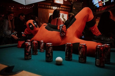 An actor dressed as Deadpool posed on a pool table with limited edition Deadpool 2 Mike’s Harder cans.