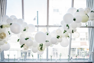 White and ivory balloon garland dotted with sprigs of eucalyptus and hints of glitter and gold hung across windows and walls.