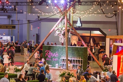 The Crispin Rosé hard cider bar displayed bottles of the new cider against a backdrop of greenery with oversize hot pink letters that read 'Rosé all day.' The branded pink bar was situated under a giant teepee with pink florals.
