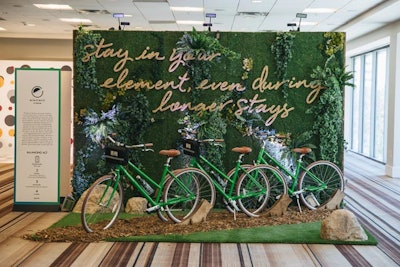 Element’s “Balancing Act” featured a living wall of moss and greenery with letters spelling out the eco-conscious brand’s tagline. The floor mimicked a natural bike path with wood chips and grass. Three green bicycles were mounted in front of the greenery as a photo op for attendees.