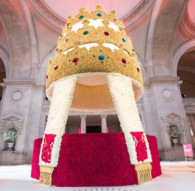 Made up of 80,000 roses, the soaring floral display echoed the papal headpiece's gilded metal work with roses in gold and off-white. The flowers at the top of the crown are faux silk blooms, which were used to reduce the total weight of the 4,000-pound structure. The triple-tiered tiara also boasted faceted Plexiglas 'jewels' that resembled rubies, emeralds, and diamonds.