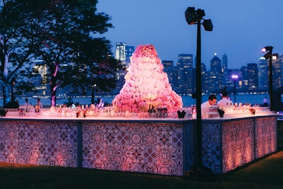 For a private corporate event on Ellis Island in New York, design firm Tinsel created Cuban-inspired decor and catering ideas. The center of the bar showcased a giant tower made from bananas; pink lighting created a unique, artsy effect.