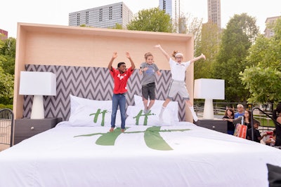 Kids jump on the oversize Holiday Inn bed produced by fabricator Id3 at the Chocolate Milk Happy Hour pop-up event in Chicago's Millennium Park.
