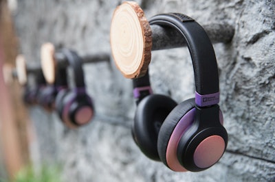 Branded noise-cancelling headphones hung from pegs adorned with wooden slices.