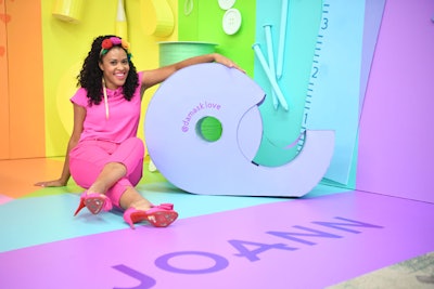 Kemp-Gerstel posed with an oversize tape prop at a rainbow-hued craft installation created by the Creative Heart Studio. The installation featured branding of event sponsor Joann and Damask Love, Kemp-Gerstel's blog.