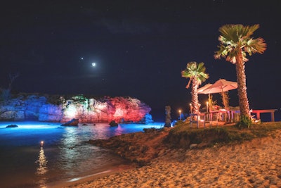 An evening event at Tobacco Bay beach included dramatic uplighting and sunken lights illuminating the cove.