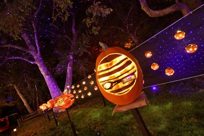 A solar system-theme display has a pumpkin for each planet; in the background, pumpkins carved with stars hang against a space-inspired backdrop.