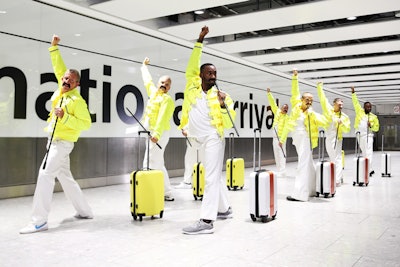 The flash mob took place in Heathrow Airport on September 5. Baggage handlers wore fake mustaches, yellow military-style jackets, and white trousers while holding suitcases in the colors of Mercury's outfit.