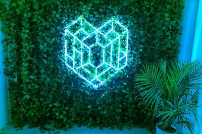 Photo ops include a wall of ivy with a geometric neon heart in the center.