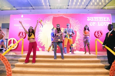 Staffers dressed in hippie attire welcomed guests to the event, which took place November 3. A pink step-and-repeat wall featured floral peace signs.