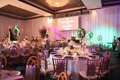 The ballroom featured tablescapes with white crocheted linens and white floral centerpieces, complemented by wood chairs. Additional decor included a peace sign topiary.