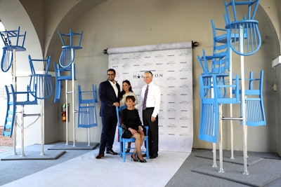 Guests posed in front a step-and-repeat flanked by upside-down chair installations inspired by Hamilton’s stage design. The chairs were painted in American Express’ blue color.
