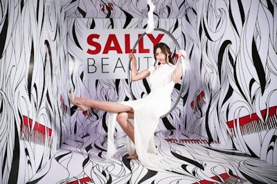 Retailer Sally Beauty built a carnival-theme booth at Beautycon that had a black-and-white illustrated backdrop representing hair strands. Guests were invited to sit on a spinning aerial hoop to pose for photos.