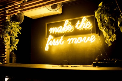A neon yellow sign above the DJ booth read 'Make the first move,' emphasizing Bumble's signature user feature.