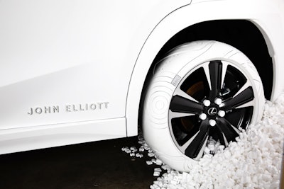 Featuring custom John Elliott branding against a unique matte white wrap, the car was staged to appear 'mid-unload,' backlit and surrounded by tens of thousands of pieces of packing styrofoam.
