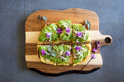 Juniper Table in Palm Springs offers a Mediterranean twist on the trendy avocado toast with an avocado flatbread. The baked flatbread is topped with avocado, turmeric, hazelnut, greens, sesame, and Serrano chili. The dish comes on a rustic wooden peel.
