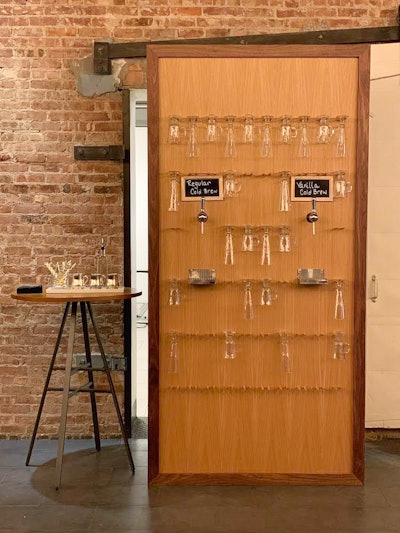 New York-based catering company Riviera Caterers offers a cold brew coffee wall for morning events. The wooden wall features hanging glass mugs, which guests can fill with regular or vanilla cold brew coffee out of spouts.