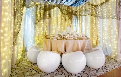 Guests perched on pearl-esque stools at a table with silver and crystal tableware with twinkling stars overhead at jewelry designer McKenzie Liautaud and Robert Verdi’s underwater-inspired dining table setup. Candles nestled among clam shells served as the centerpiece.