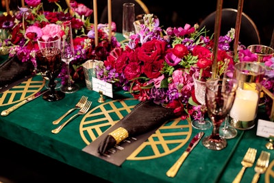 The tables had jewel-tone floral centerpieces and an emerald velvet tablecloth from BBJ Linen. Not My Dish provided on-theme gold place settings.