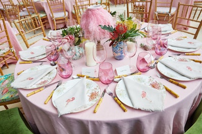 Pink tablecloths were set with chargers printed with floral branches, painted pink glassware, bamboo flatware, feather-decorated lampshades, and napkins embroidered with pink flamingos.
