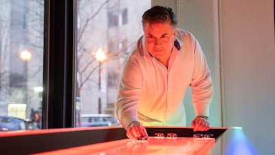 A guest lines up a shot on the LED Shuffleboard table at the Snap Entertainment Open House at AJAX DC.