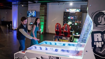 A man and woman go head to head for the high score in a fun game of Skeeball at the Snap Entertainment Open House at AJAX DC.