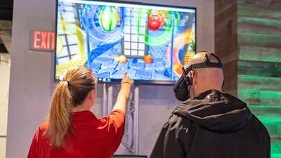 A guest is guided through a Virtual Reality gaming experience on the Oculus Rift headset at the Snap Entertainment Open House at AJAX DC.