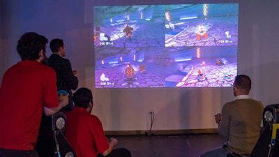 A video game station projects Mario Kart on a giant white wall for guests to play at the Snap Entertainment Open House at AJAX DC.