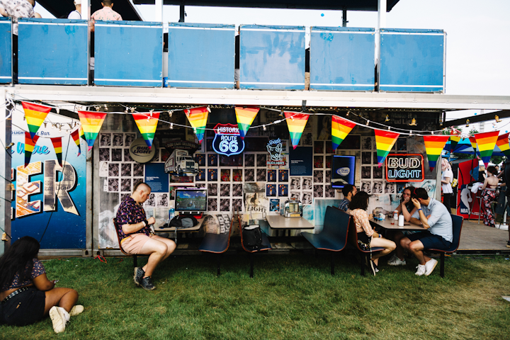The back of the activation featured imagery welcoming guests, along with dive bar-inspired decor and seating. The wall was plastered with vintage Bud Light ads and neon signs.